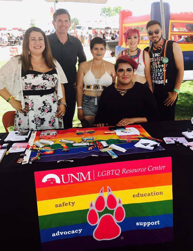 Group of students behind a table with the LGBTQ banner